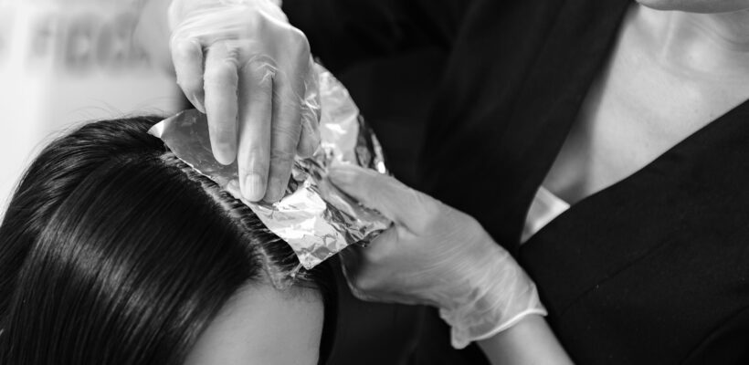 beauty concept, hairstylist holding foil on head of a client